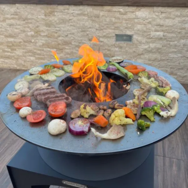 Brasero plancha Fiesta 75 cm en acier corten avec feu central et légumes grillés en situation d'utilisation