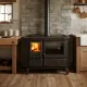 Cuisinière à bois Gardenia XXL en acier noir avec four et foyer allumé installée dans une cuisine rustique