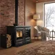 Cuisinière à bois Alaska 12 kW noire avec four installée dans un salon moderne avec mur en brique