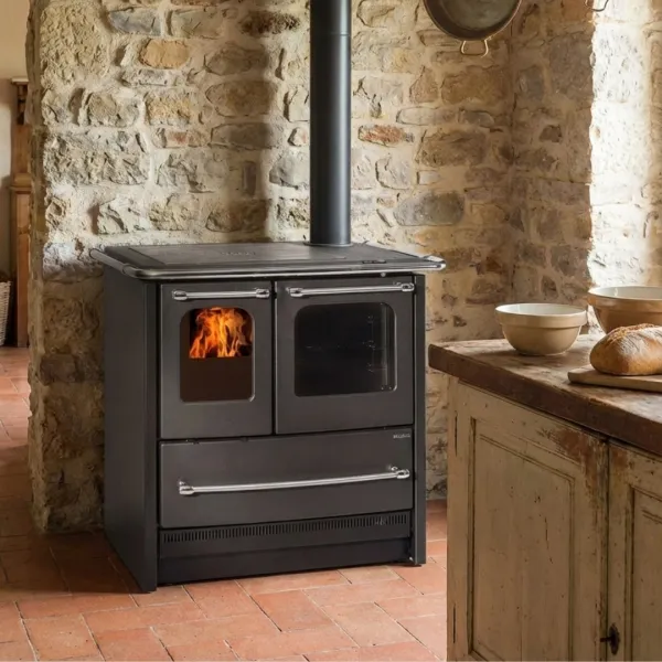Cuisinière bois SOVRANA EASY EVO anthracite avec four et foyer allumé installée dans cuisine rustique