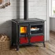Cuisinière à bois Milly en acier noir avec four et détails rouges, installée dans une cuisine rustique