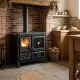 Cuisinière à bois Gardenia noire avec four installée dans une cuisine rustique avec feu allumé