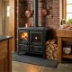 Cuisinière à bois Gardenia noire avec four et foyer allumé installée dans une cuisine rustique avec conduit