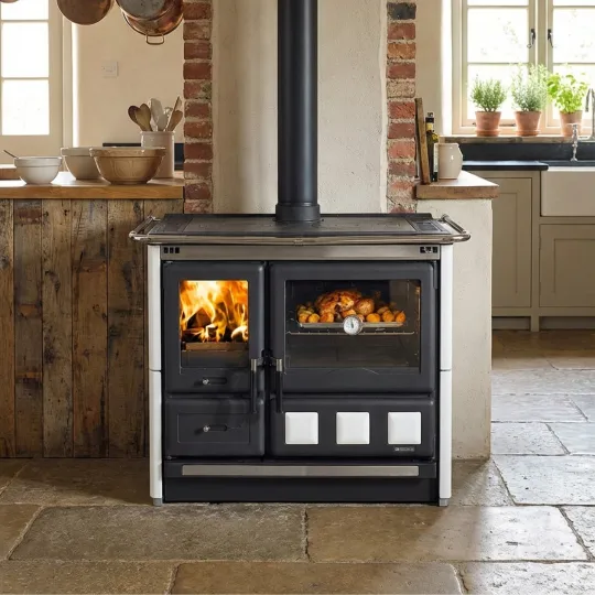 Cuisinière à bois Rosa XXL en fonte noire et blanche avec four, installée dans une cuisine rustique