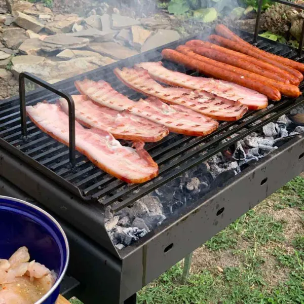 Petit barbecue au charbon avec lard et saucisses en cuisson