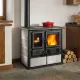 Cuisinière à bois Rosa Sinistra Reverse 8 kW installée près d’un rangement à bûches