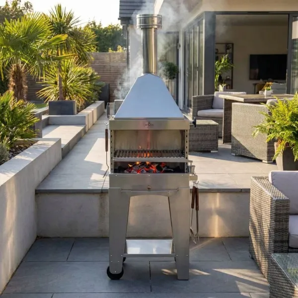 Barbecue au charbon Foxy en inox installé sur une terrasse extérieure près d’une cuisine de jardin