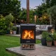 Barbecue à bois Hestia 300 Heat & Grill avec foyer allumé, installé dans un jardin aménagé en soirée